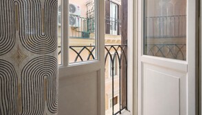 A window with a patterned curtain, a balcony with a metal railing, and a view of a building with air conditioning units. - Elegantis Pantheon Suite near Piazza Navona - Historic Centre (Roma)