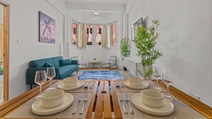 En matplats med ett bord dukat för sex personer, en blå matta och en grön soffa i bakgrunden.