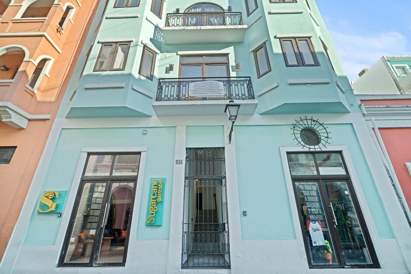 Un edificio de varios pisos con fachada azul claro, un balcón con barandilla de metal y un letrero de 'Subcarne Gastrobar' en la planta baja.