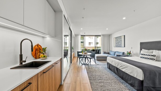 Un appartement moderne comprenant une cuisine, un coin repas et une chambre.