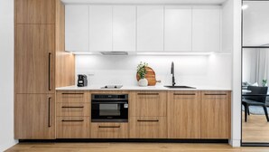 Une cuisine moderne avec des meubles en bois, un four encastré, une machine à café et un évier.