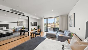 Une chambre d’hôtel moderne dotée d’un lit, d’un coin salon, d’une table à manger et d’un balcon avec vue.