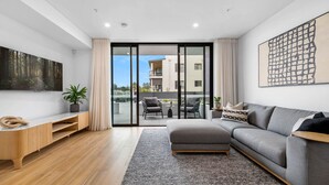 Un salon moderne avec un canapé gris, un meuble de rangement en bois et une grande fenêtre.