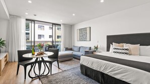 Une chambre d’hôtel moderne équipée d’un lit, d’un canapé, d’une table à manger et de grandes fenêtres.