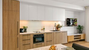 Una cocina moderna con armarios de madera, horno empotrado, lavamanos y comedor con mesa y sillas.