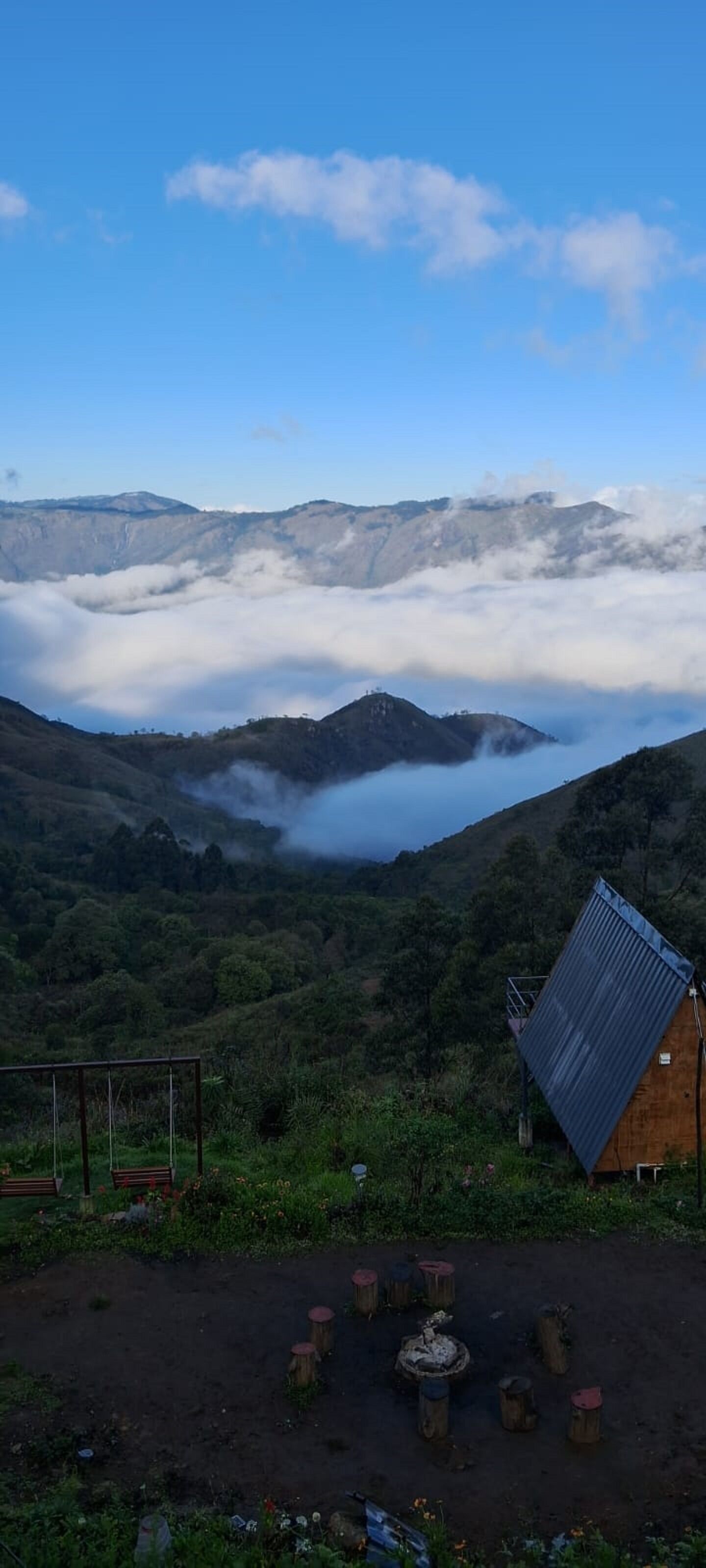 Un paisaje montañoso con una cabaña de madera y un conjunto de columpios.