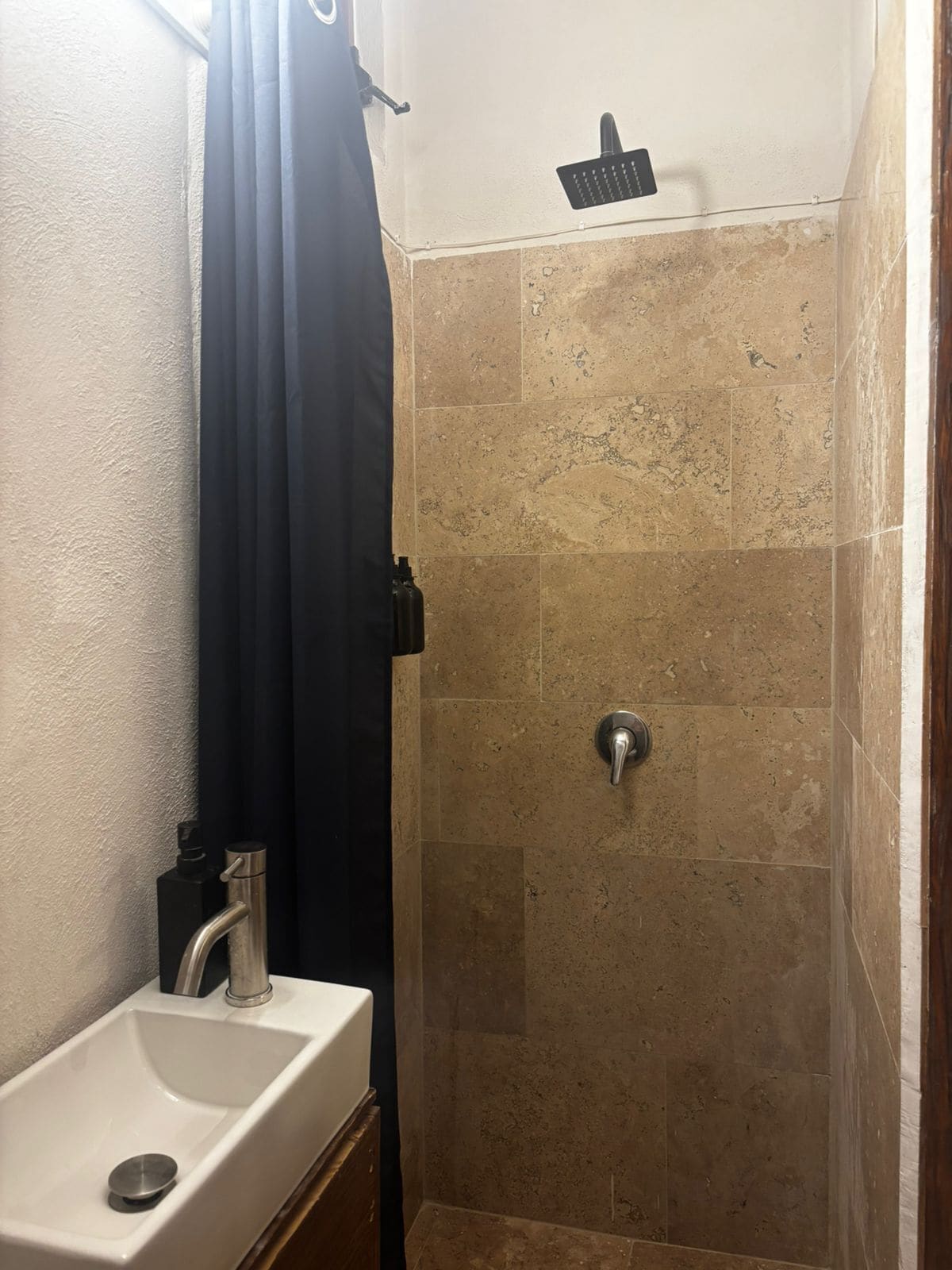 A bathroom with a shower, a sink, and a towel rack.