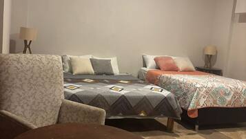 Quarto com duas camas, uma cadeira e uma mesinha.