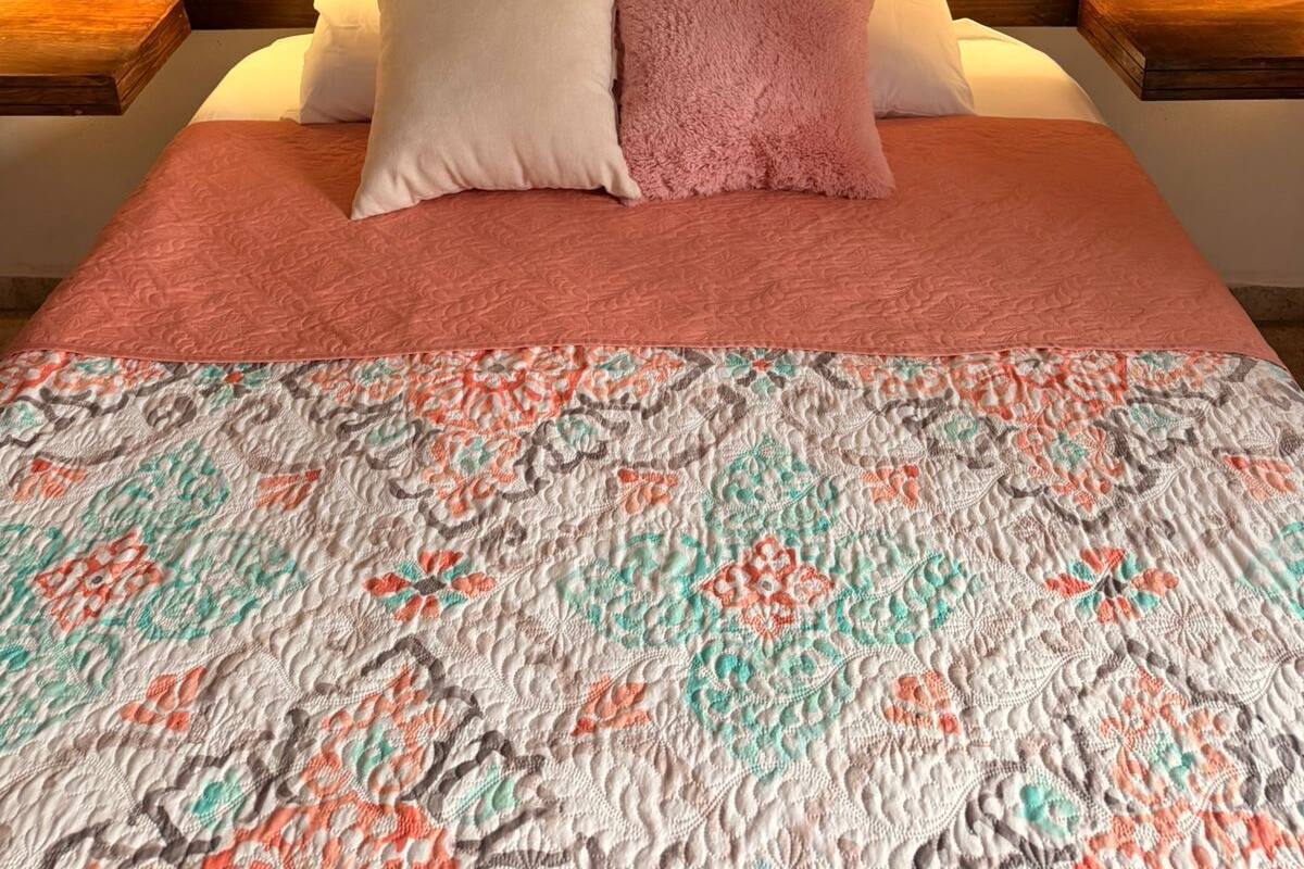 A bed with a patterned quilt, two pillows, and a wooden headboard.
