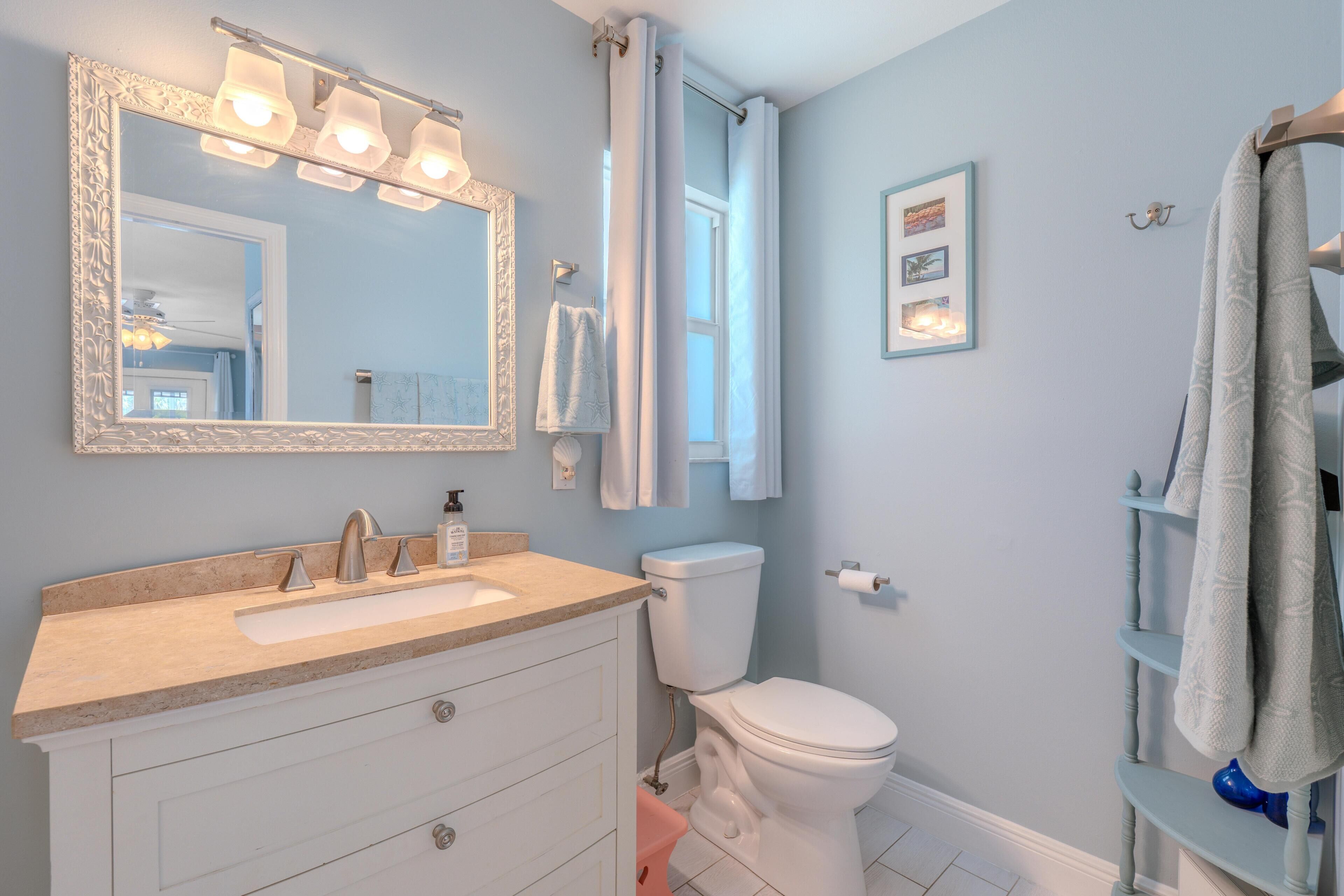 A bathroom with a sink, mirror, toilet, and towel rack.
