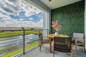 Un balcón con vista a un río, un muro verde y una mesa con sillas.