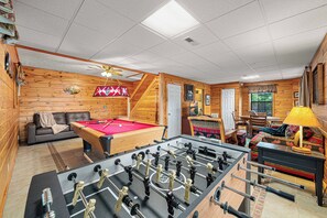 A room with a pool table, foosball table, sofa, and a ceiling fan. - Lakefront · Dock · 8 Acres · Hot Tub · 2 Fire Pits (Sevierville)