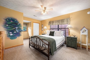 A bedroom with a bed, a nightstand, a dresser, a ceiling fan, and a wall mural. - Lakefront · Dock · 8 Acres · Hot Tub · 2 Fire Pits (Sevierville)