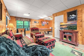 A cozy cabin interior with a pool table, comfortable seating, and a television. - Lakefront · Dock · 8 Acres · Hot Tub · 2 Fire Pits (Sevierville)