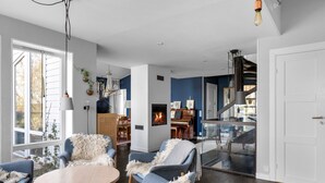 A modern living room with a fireplace, a dining area, and a staircase leading to an upper level.