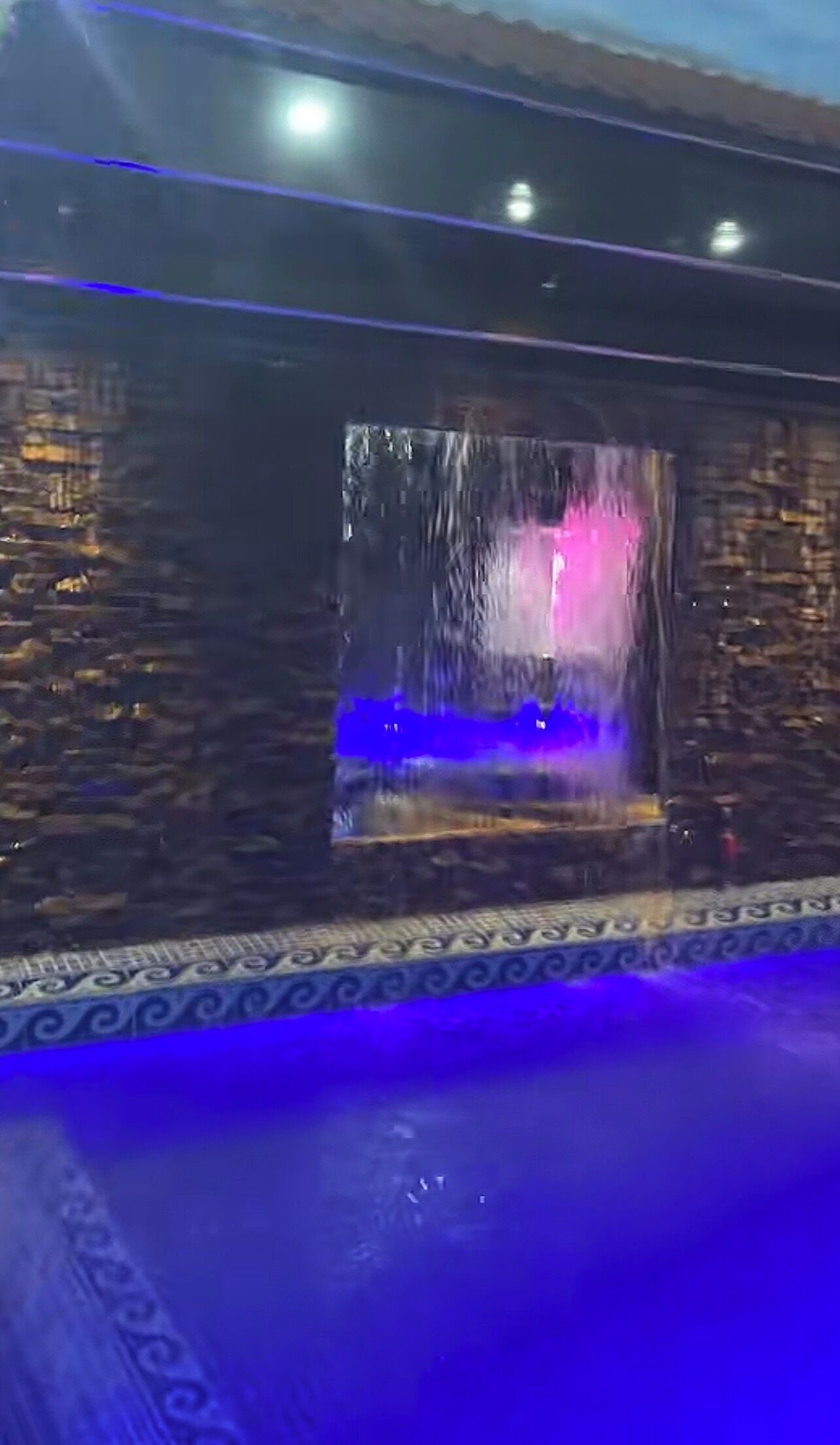 A pool with a water feature and a patterned border.