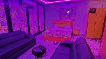 Een kamer met een bed, een massagetafel, een bank en een plafondventilator.