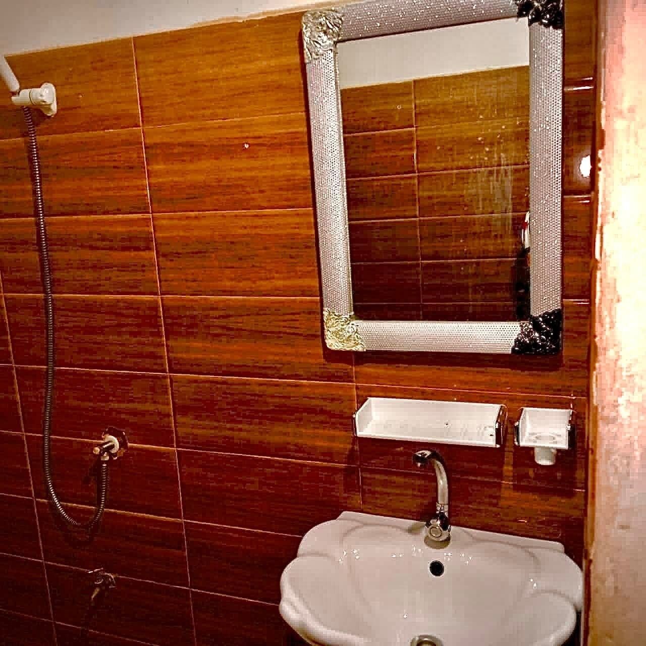 Un baño con baldosas de madera, un lavabo, un espejo y una ducha.