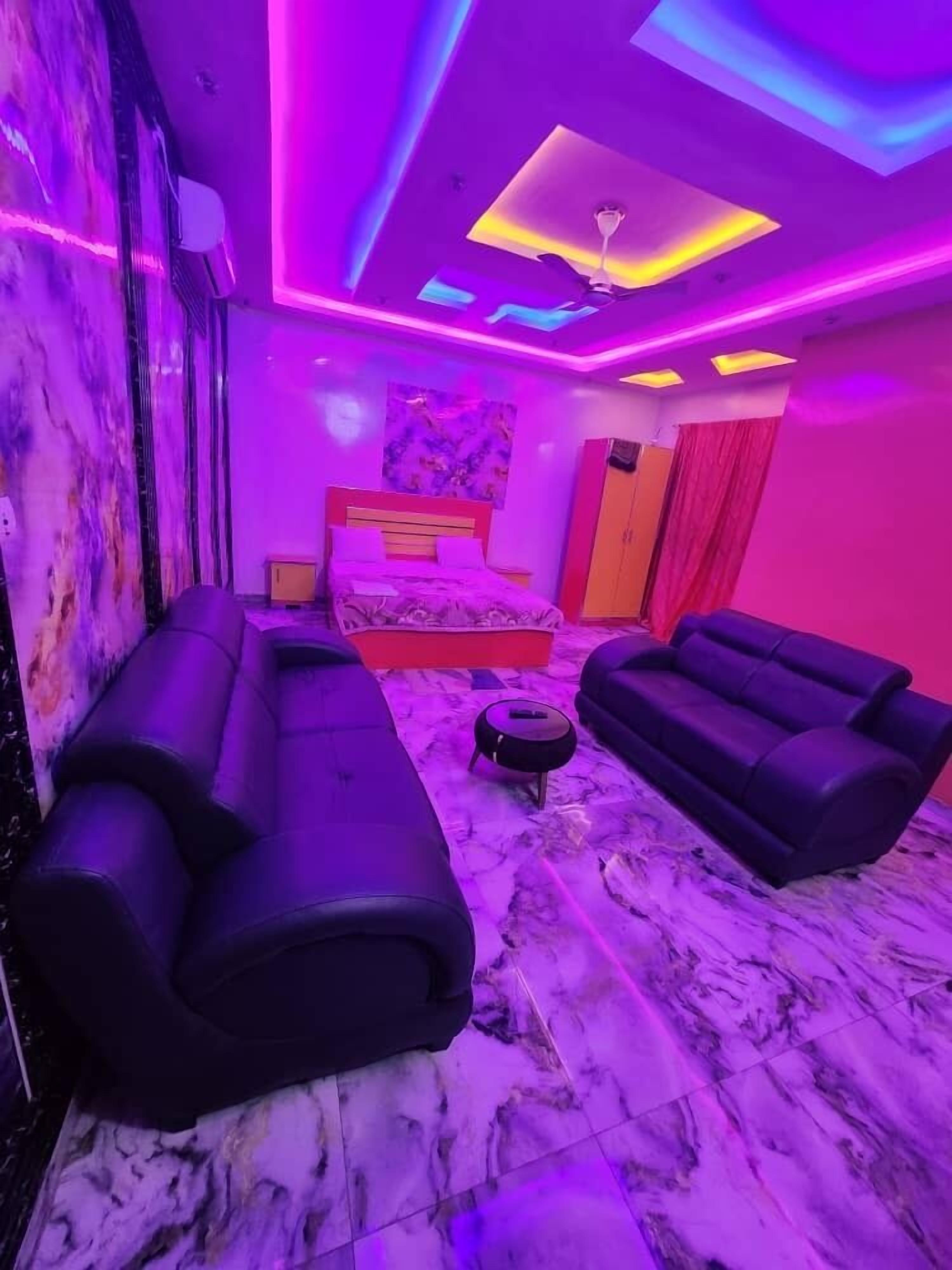 Un dormitorio moderno con cama, dos sofás, una mesita y un ventilador de techo.