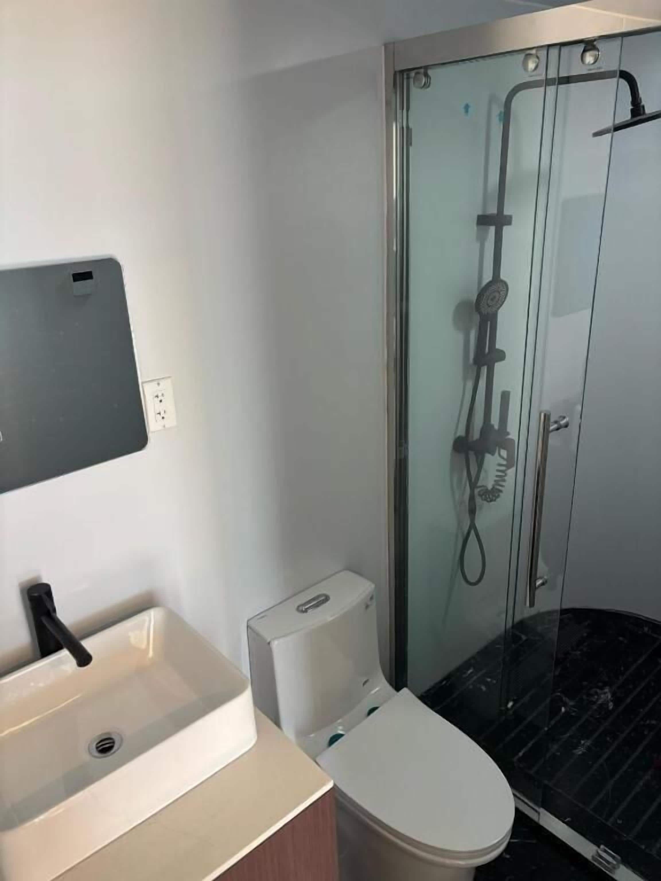Un baño moderno con ducha acristalada, inodoro y lavamanos.