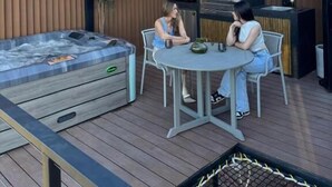 Eine Außenpatio mit einem Whirlpool, einem Grill und einem runden Tisch mit Stühlen.