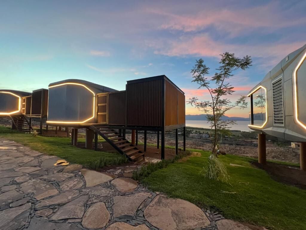 Un edificio moderno con una escalera que lleva a una terraza, rodeado de senderos de piedra y vegetación.