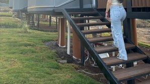 Eine Person geht eine Holztreppe zu einem modernen Gebäude mit einem gewölbten Dach hinauf.