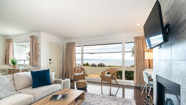 A modern living room with a sofa, coffee table, and a fireplace. - Beachfront · sunrise ocean views, 3BR, BBQ (Campbell River)