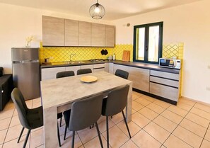 Eine moderne Küche mit Esstisch, Stühlen, einem Kühlschrank und einem Fenster.
