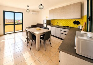 Eine moderne Küche mit Essbereich, großen Fenstern und einer gelben Spritzschutzwand.