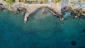Vista aérea de una zona costera con un puente de piedra que conduce a una costa rocosa.