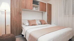 Un dormitorio ordenado con cama, mesita de noche, lámpara y un armario de madera.