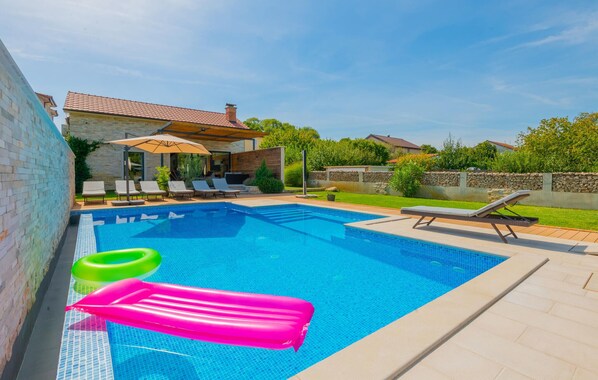 Ein Schwimmbecken mit Liegestühlen und Luftmatratzen.
