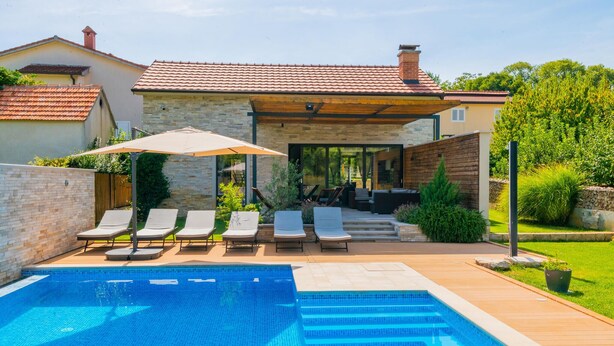 En swimmingpool med liggestole og en overdækket terrasse.