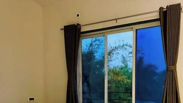 A bedroom with a large bed, a sliding glass door, and curtains. - Scarlet Stays (Alibag)