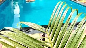 A swimming pool with a lifebuoy, surrounded by buildings with a sign for 'Scant Resort'. - Scarlet Stays (Alibag)