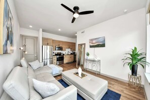 A modern living room with a sofa, coffee table, and a ceiling fan. - Luxury Houston Apartment Rooftop Pool City Views & King Beds! (Houston)