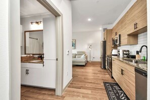 A modern kitchen with wooden cabinets, a microwave, and a refrigerator. - Luxury Houston Apartment Rooftop Pool City Views & King Beds! (Houston)