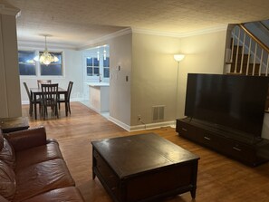 A living room with a sofa, a coffee table, a TV, and a staircase. - Enjoyable 3-bedroom townhome with AC in vibrant Baltimore (Baltimore)