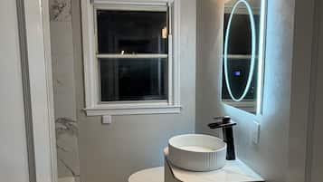 Une salle de bain avec des toilettes, un lavabo avec un miroir et une fenêtre.