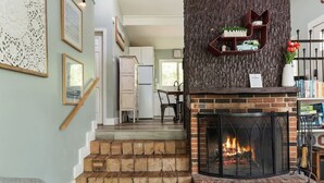 Ein Wohnzimmer mit Kamin, einer Treppe und einer Küche im Hintergrund.