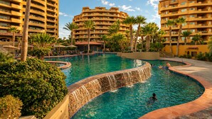 A resort with a large pool, palm trees, and high-rise buildings. - Villa Dos Sirenas | Luxury Beachfront 5BR | 5BA | detached Casita | Bella Sirena (Puerto Peñasco)