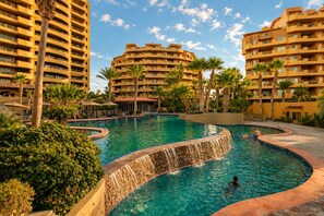 Un resort con una piscina grande, palmeras y edificios altos.