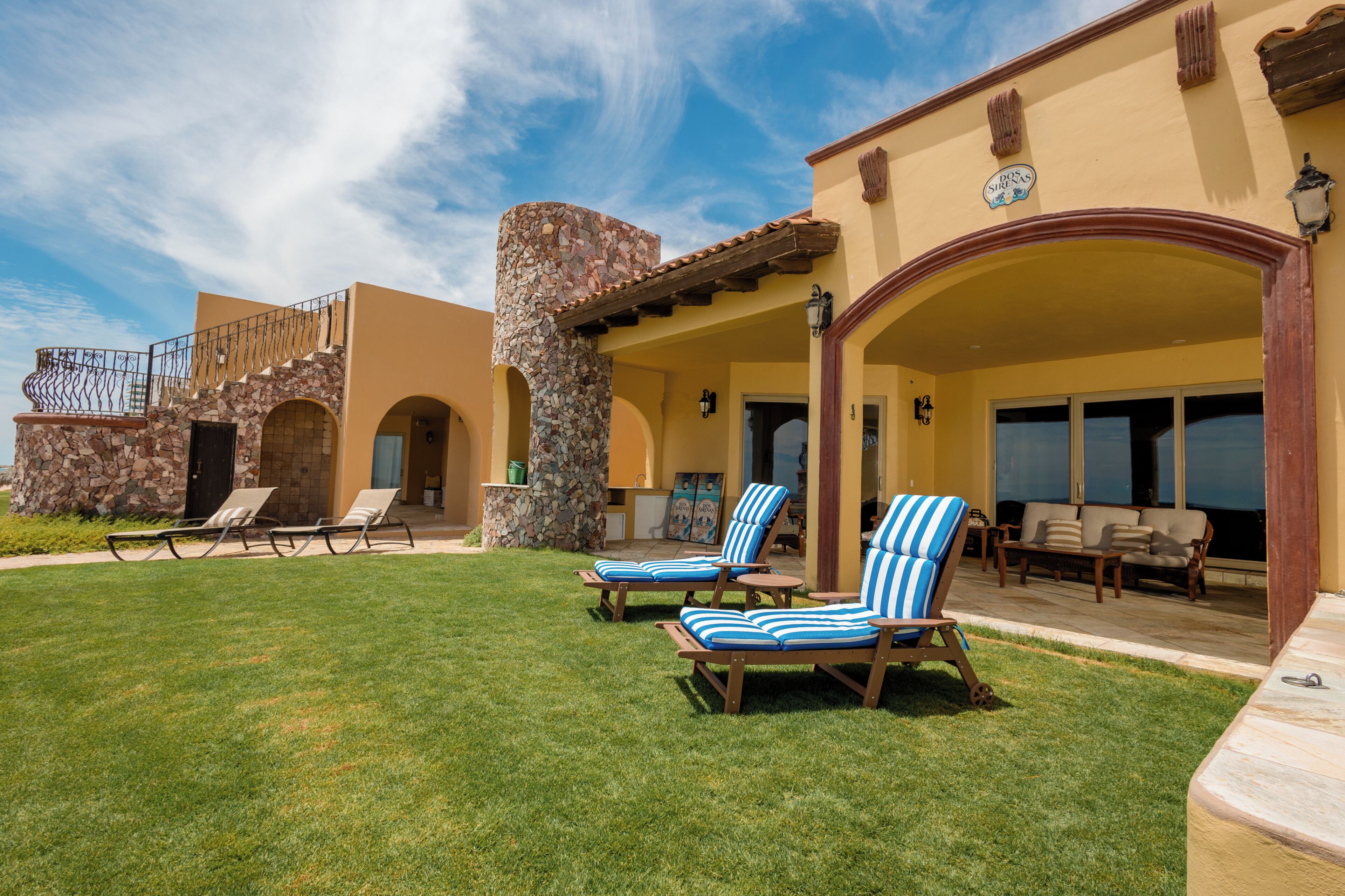 Un hotel con un patio cubierto, asientos al aire libre y un pilar de piedra.