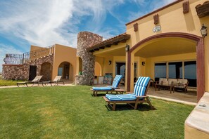 Un hotel con un patio cubierto, asientos al aire libre y un pilar de piedra.