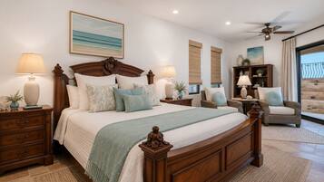 A bedroom with a large bed, two nightstands, a ceiling fan, and a view of the outdoors.