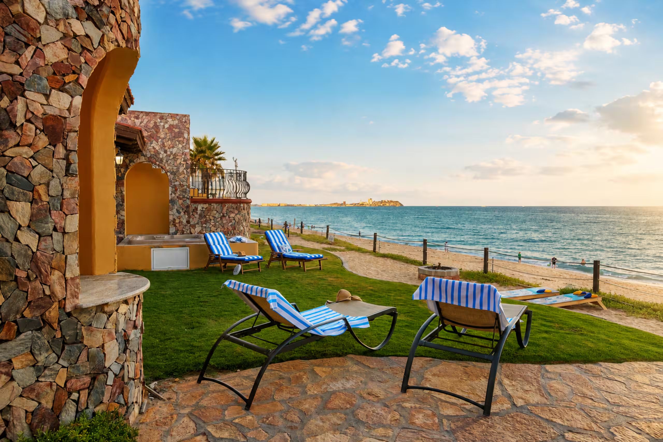 Une terrasse avec des murs en pierre, une piscine et des chaises longues donnant sur l’océan.