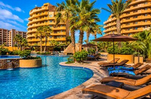 A resort pool area with lounge chairs and palm trees.