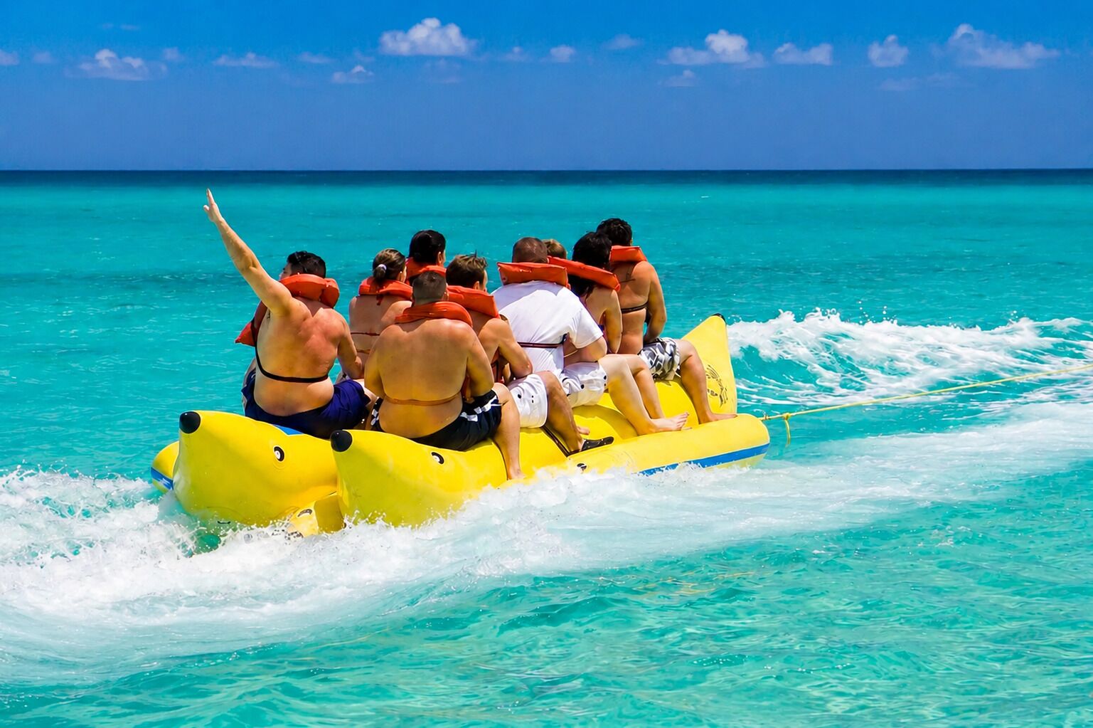 A group of people on a yellow inflatable raft in turquoise water.