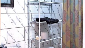 Un baño con un lavamanos blanco, un inodoro y una estantería metálica.